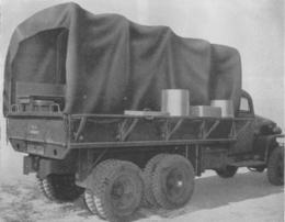 A side view of an Army kitchen truck. The troop seets have been relocated to outside the truck to give the cooks storage shelves.